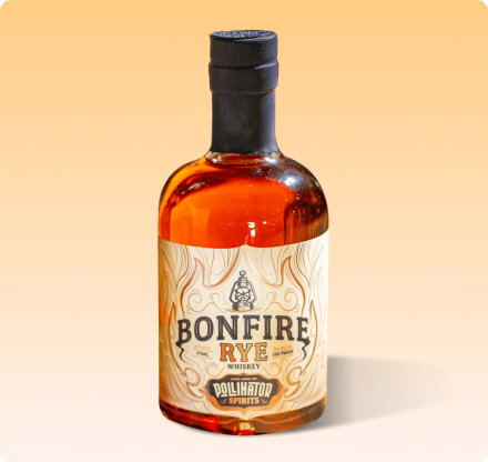 A bottle of Bonfire Rye whiskey with a label that has flame-like graphics and text, set against an orange background.