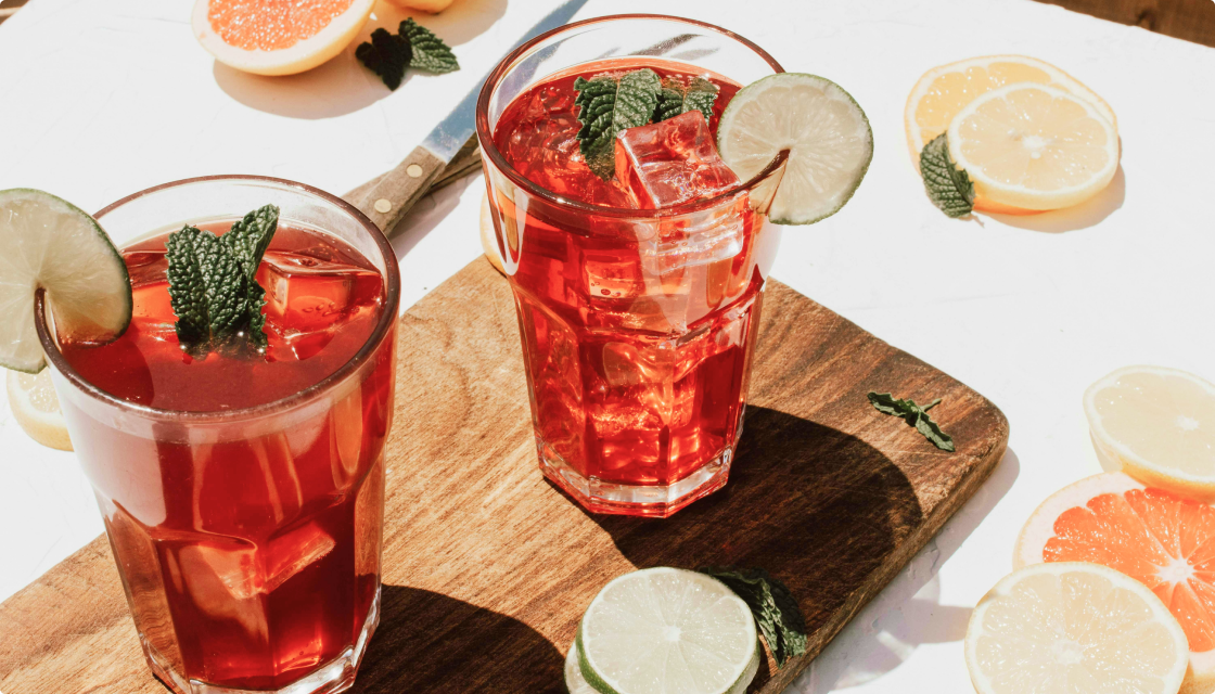 A cozy autumn scene with a glass of Bonfire Rye cocktail surrounded by fall leaves and spices