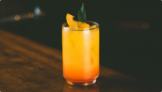 Peach & Rye Smash cocktail with mint garnish and fresh peach slices in a rocks glass
